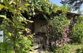 Schaugarten Towanda, © "Natur im Garten" Ein blühender Garten mit Rosen und einer überdachten Holzstruktur.