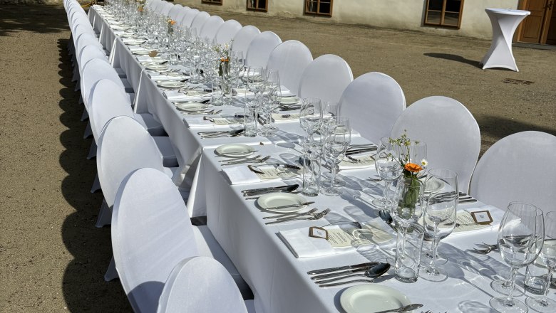 Tafeln im Weinviertel, © Weinviertel Tourismus GmbH Lange Tafel im Freien mit weißer Tischdecke und Gedecken vor einem historischen Gebäude.