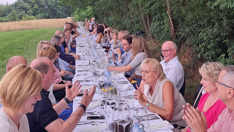 Tafeln im Weinviertel, © Weinviertel Tourismus GmbH Menschen sitzen an einem langen Tisch im Freien unter Bäumen mit Lichterkette.