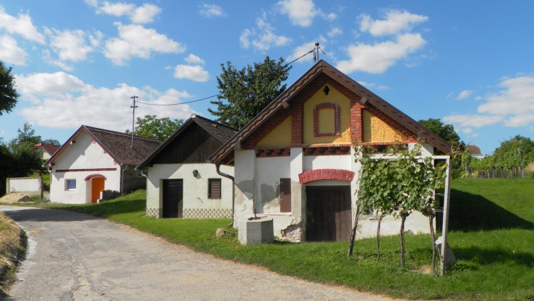 Kellergasse Zwingendorf, © Adolf Schmid Traditionelle Weinkeller in einer ländlichen Umgebung mit blauem Himmel und Wolken.