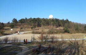 Buschberg, © Gemeinde Gnadendorf Landschaft mit Hügel, Wald und Radarkuppel unter blauem Himmel.
