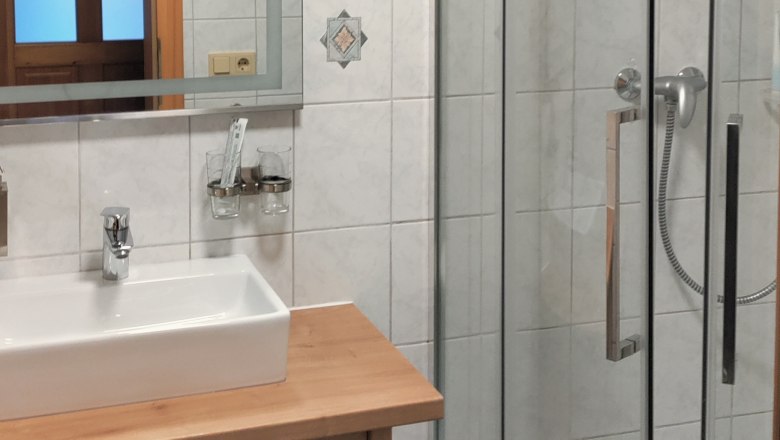 Badezimmer, © Arkadenhof Schneider Modernes Badezimmer mit Dusche, Waschbecken und Spiegel.