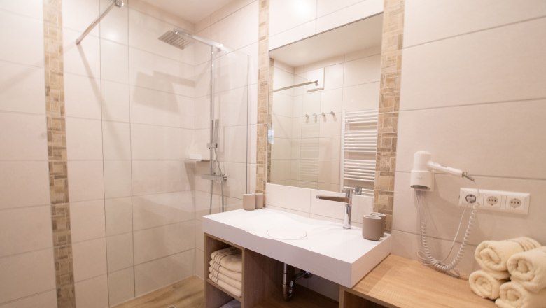 Rebenhof, Ferienwohnung, © Rebenhof Modernes Badezimmer mit Dusche, Waschbecken und Handtüchern.