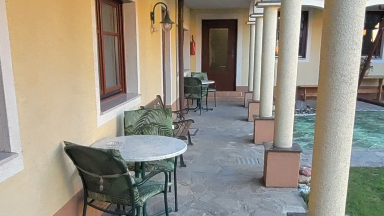 Im Arkadenhof, © Arkadenhof Schneider Ein Arkadenhof mit Steinboden, gelber Wand und Säulen. Tische und Stühle stehen entlang der Wand.