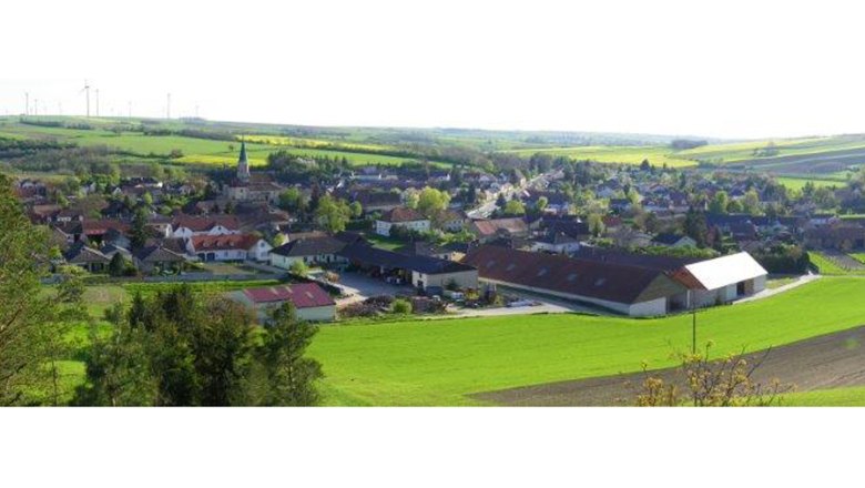 Hauskirchen, © Gemeinde Hauskirchen Landschaft mit Dorf und Kirche, umgeben von Feldern.