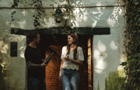 Kellergasse Schindergasse, © Weinviertel Tourismus GmbH / Michael Reidinger Zwei Personen stehen vor einem Weinkeller in der Schindergasse in Herrnbaumgarten.