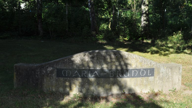 Trinkbrunnen Maria Bründl, © Weinviertel Tourismus GmbH Stein mit der Inschrift 'Maria-Bründl' in einem schattigen Waldgebiet.