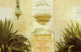 Jungblutdenkmal, © Erdäpfelmuseum Prinzendorf Denkmal mit Inschrift, umgeben von Pflanzen und einem Korb mit Kartoffeln und Sonnenblumen.