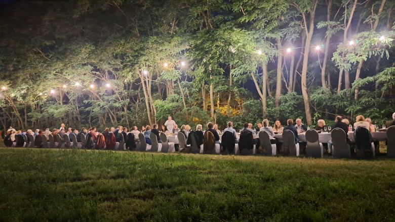 Tafeln im Weinviertel, © Weinviertel Tourismus GmbH Menschen sitzen an einem langen Tisch im Freien, umgeben von Bäumen und Lichterketten.