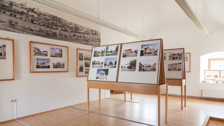 Innenansicht eines Museumsraums mit Fototafeln und historischen Bildern an den W&auml;nden.