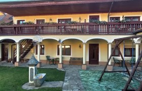 Innenhof mit Arkaden, Balkon, Schaukel und Brunnen.