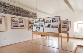 Innenansicht eines Museumsraums mit Fototafeln und historischen Bildern an den W&auml;nden.