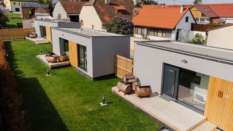 Moderne Appartements mit Holzfass-Dekoration auf grüner Wiese.