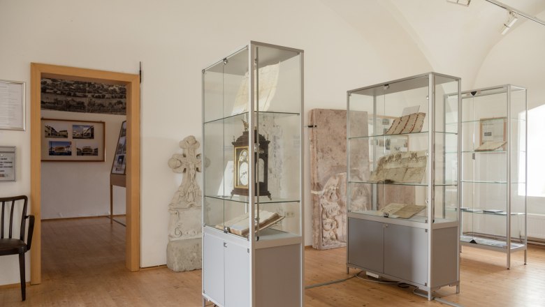 Innenansicht eines Museums mit Vitrinen, die historische Dokumente und Objekte enthalten.