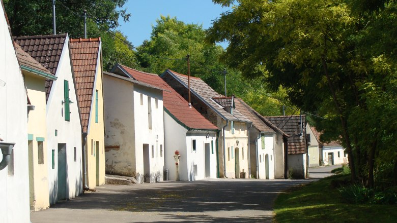 Reihe von Weinkellern in der Kellergasse Altlichtenwarth, umgeben von B&auml;umen.