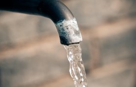 Nahaufnahme eines Wasserhahns mit fließendem Wasser.