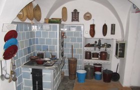 Historische K&uuml;che mit blau gefliestem Herd und alten K&uuml;chenutensilien.