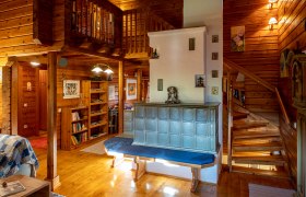 Gemütliches Wohnzimmer mit Kachelofen, Holzwänden und Treppe.