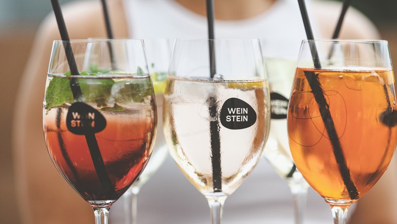 Nahaufnahme von Weingläsern mit verschiedenen Getränken und Strohhalmen.