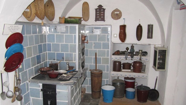 Historische K&uuml;che mit blau gefliestem Herd und alten K&uuml;chenutensilien.