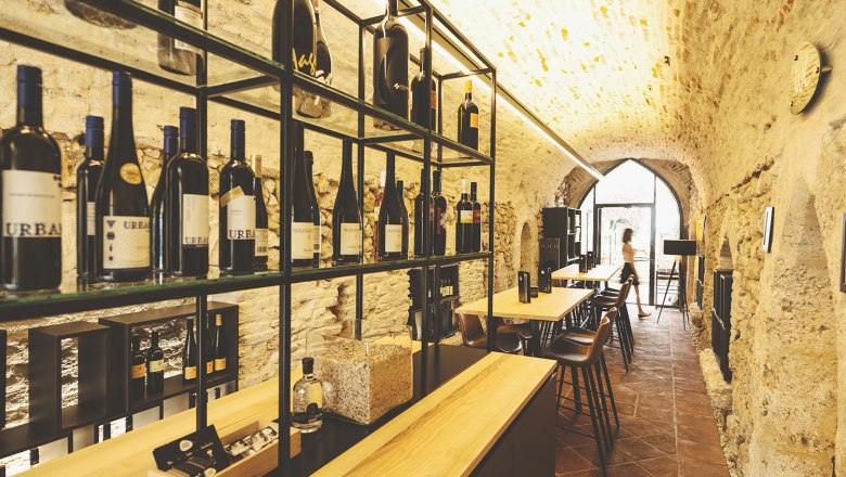 Weinkeller mit Flaschenregalen und Tischen in einem Gewölbe.