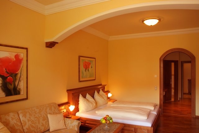 Gem&uuml;tliches Hotelzimmer mit Doppelbett, Sofa und Gem&auml;lden an den W&auml;nden.