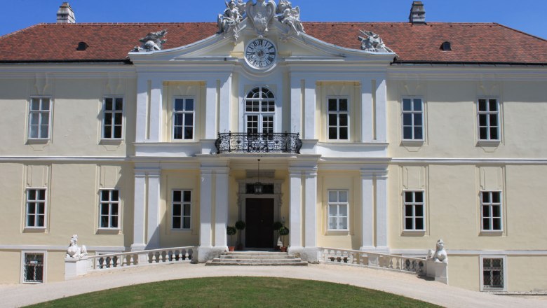 Frontansicht von Schloss Liechtenstein mit Uhr und Skulpturen auf dem Dach.