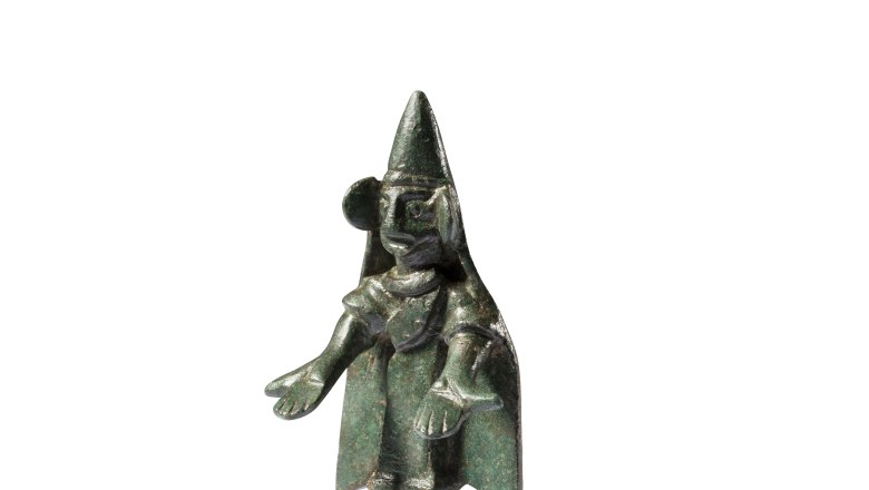 Bronzestatuette einer betenden Figur mit spitzem Hut und ausgestreckten Armen.
