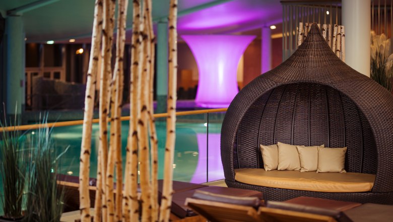 Entspannungsbereich mit Liegen und Korbsessel in einem Spa.