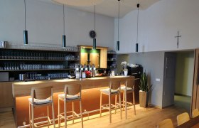 Innenansicht einer Bar mit Holztheke und Barhockern.