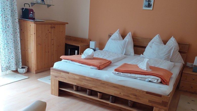 Gemütliches Schlafzimmer mit Doppelbett, Holzmöbeln und oranger Wand.