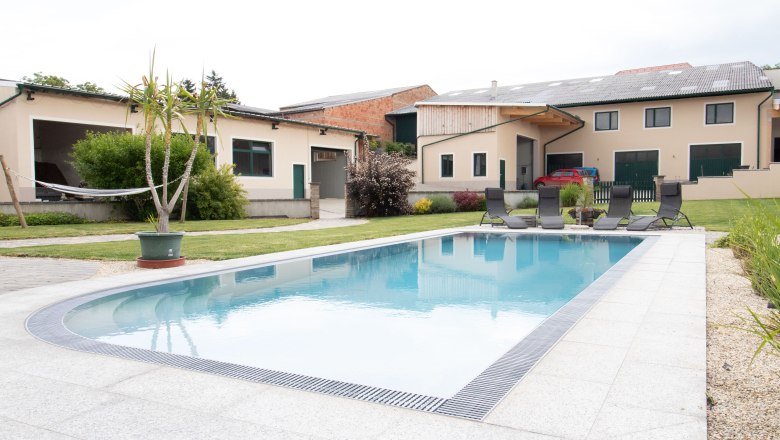 Rebenhof, Ferienwohnung, © Rebenhof Ein moderner Hof mit einem großen Swimmingpool und Liegestühlen im Vordergrund.
