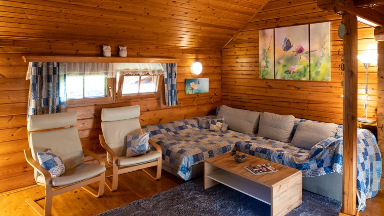 Gemütliches Wohnzimmer in einer Holzhütte mit Sofa, Sesseln und Dekoration.