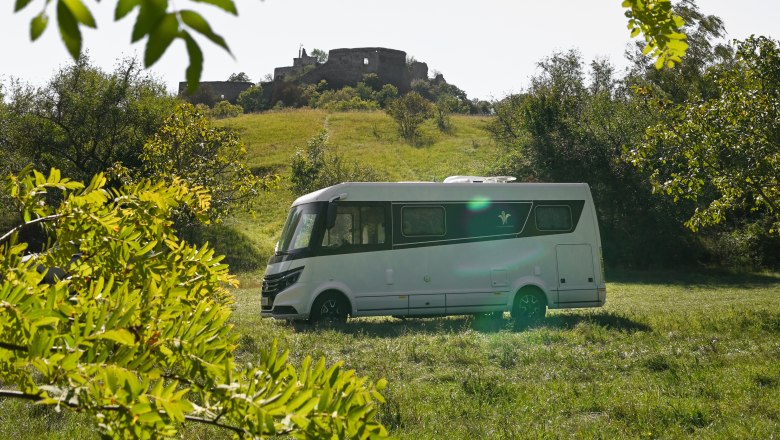 Wohnmobil auf einer Wiese vor einer Burgruine in Falkenstein.