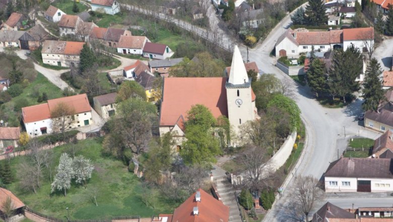 Luftaufnahme einer Kirche in einem Dorf mit umliegenden H&auml;usern und Stra&szlig;en.