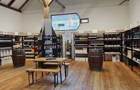 Innenansicht einer Vinothek mit Weinregalen und Holztischen.