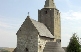 Historische Wehrkirche mit steinernem Turm und Spitzdach.