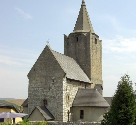 Historische Wehrkirche mit steinernem Turm und Spitzdach.