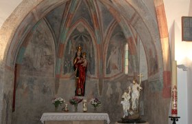 Innenansicht einer Kapelle mit Fresken und Statuen.