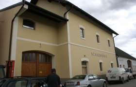 Au&szlig;enansicht eines gelben Geb&auml;udes mit der Aufschrift 'Schaum&uuml;hle'.