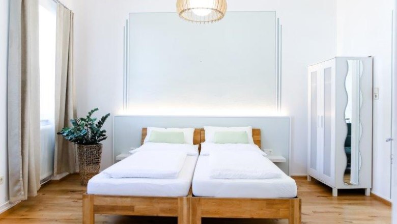 Modernes Gästezimmer mit zwei Einzelbetten, einem Kleiderschrank und einer Pflanze.