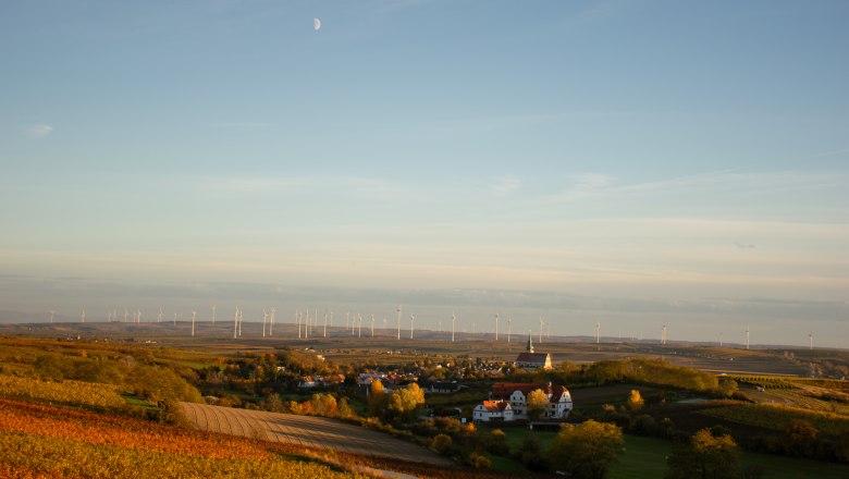 Landschaft mit Windr&auml;dern und Dorf im Vordergrund bei Sonnenuntergang.